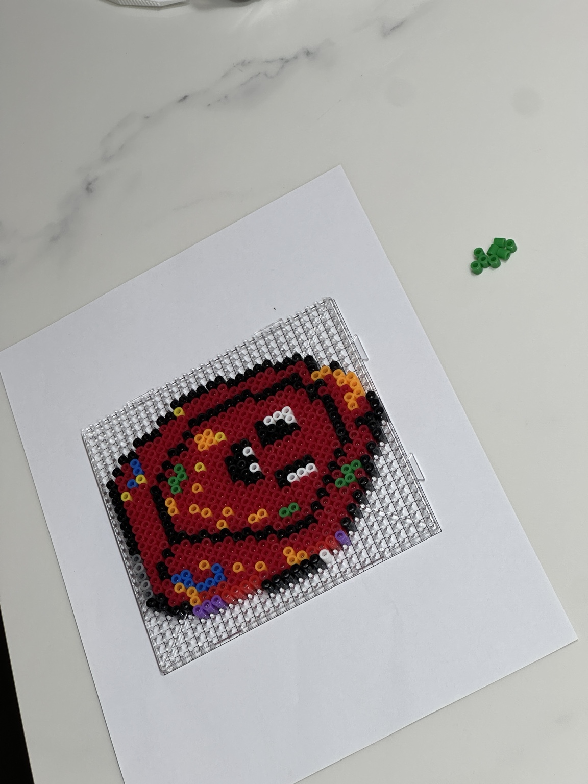 A colourful fuse bead design taking shape on a clear pegboard